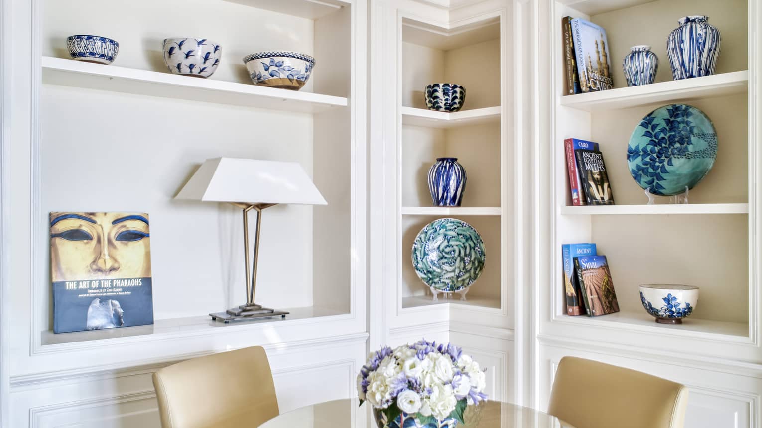 Premium Executive Suite dining area with two-seater round glass table, built-in shelves lined with colourful artefacts