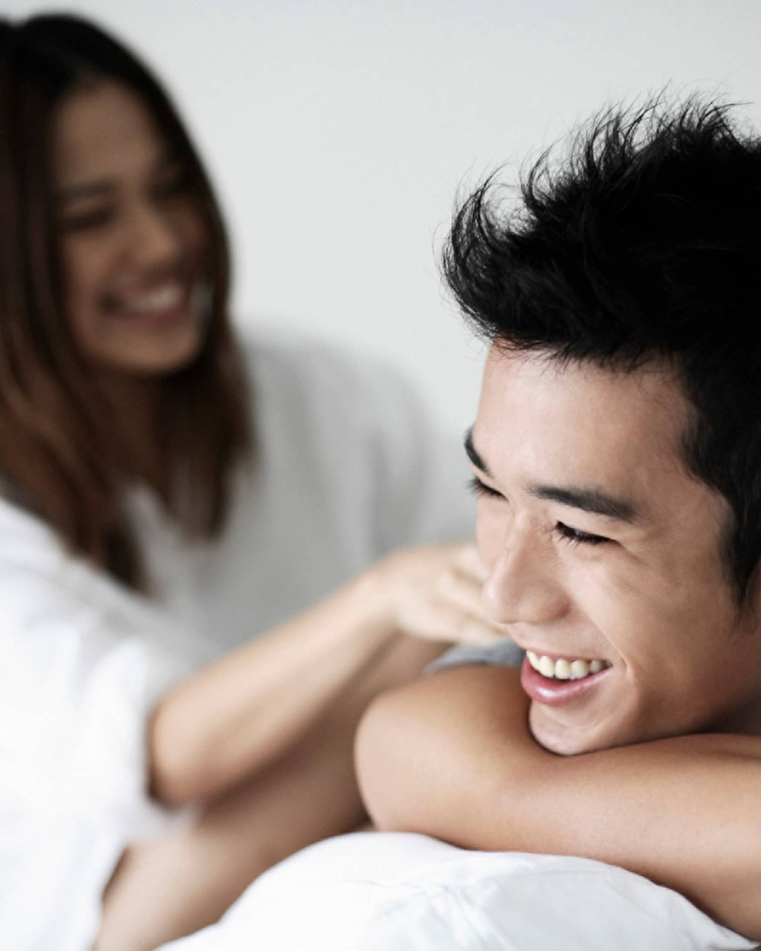 Smiling man rests chin on arms, woman in background