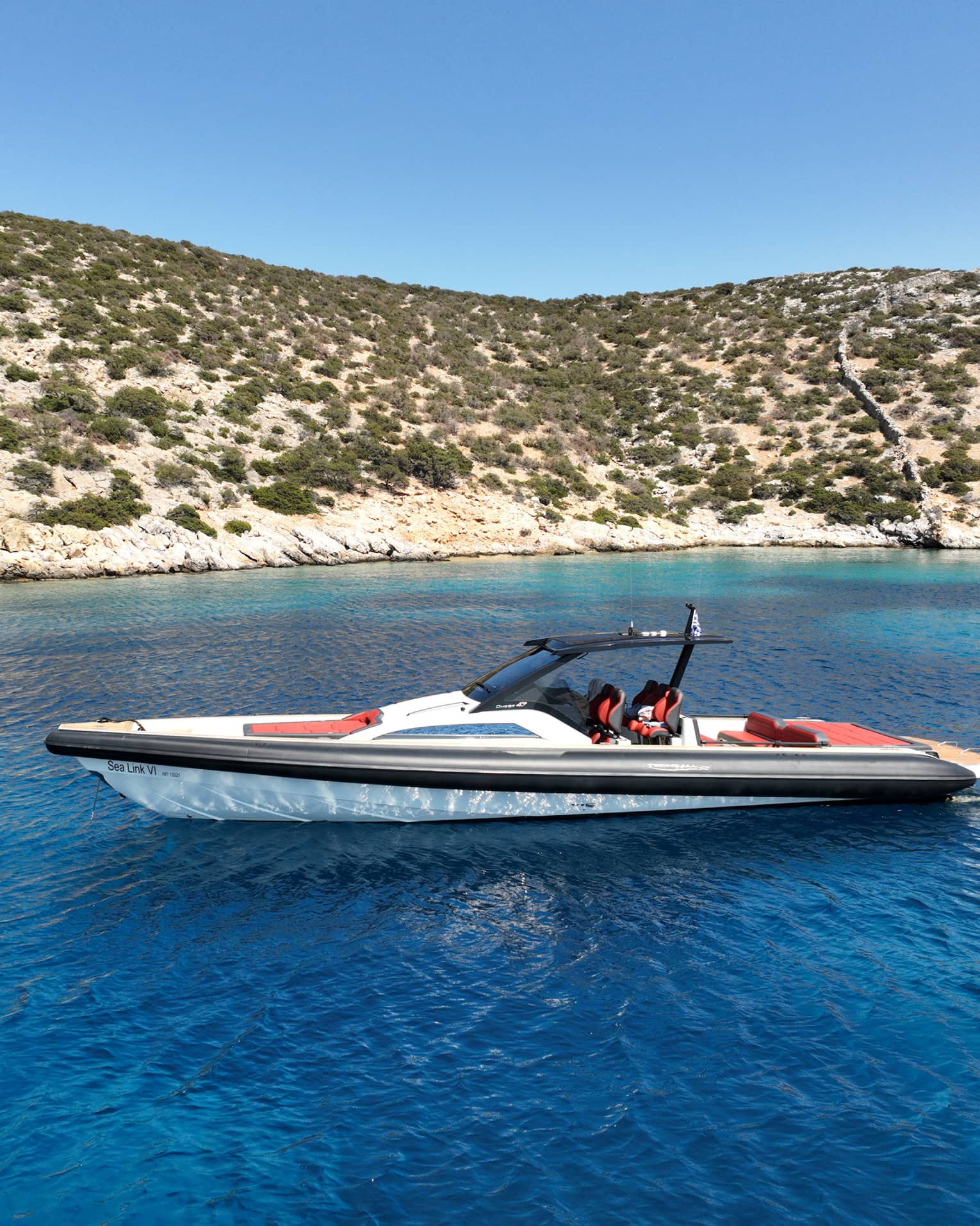 People swim behind a luxury boat in the blue waters close to the coast.