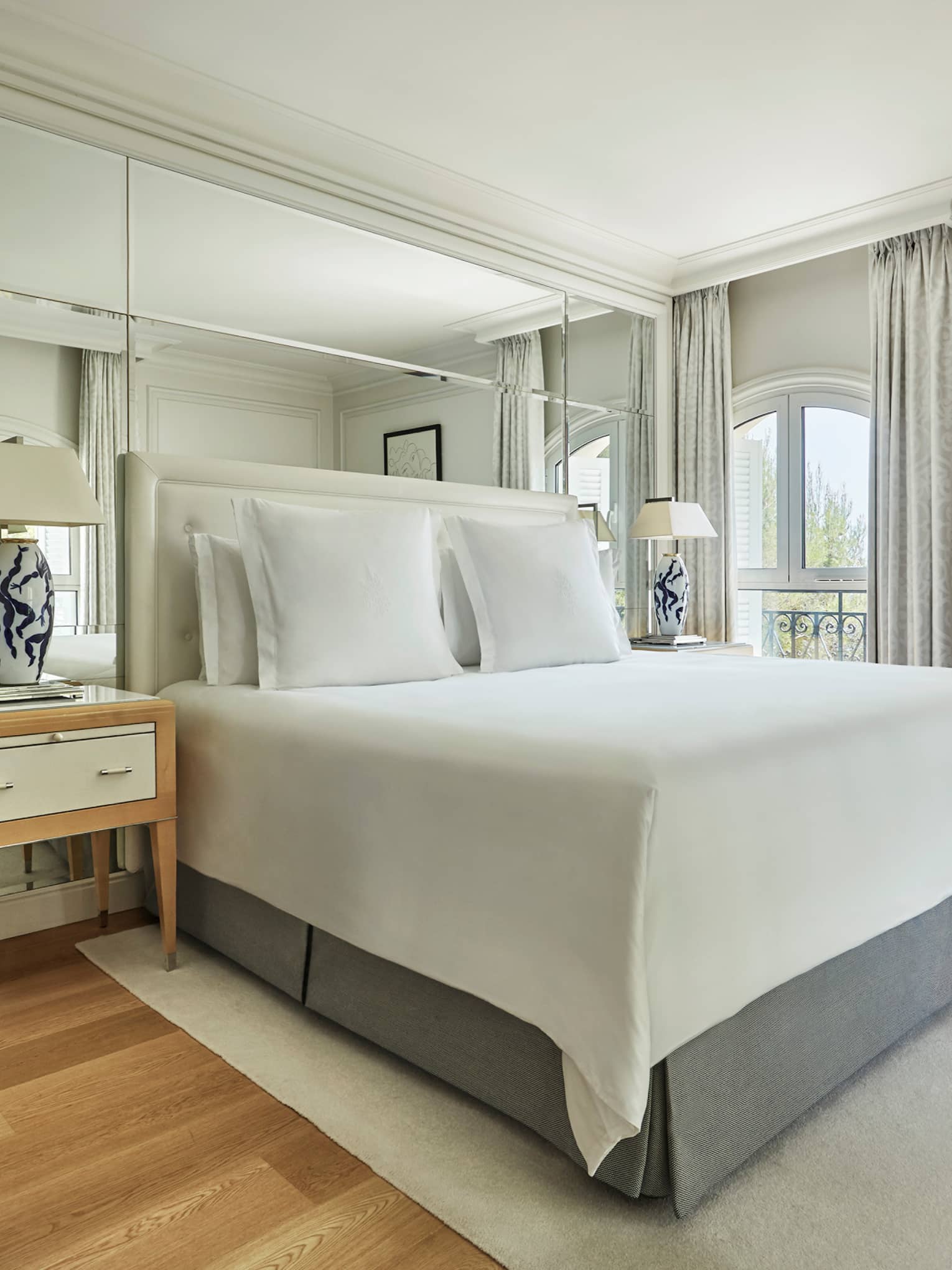 Four Seasons Pinewood Suite bed, nightstand with black-and-white lamps, wood floors