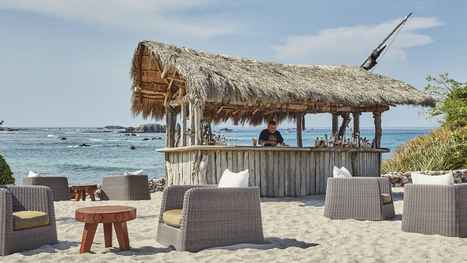 A man works at shack bar on the beach, with the water in the background