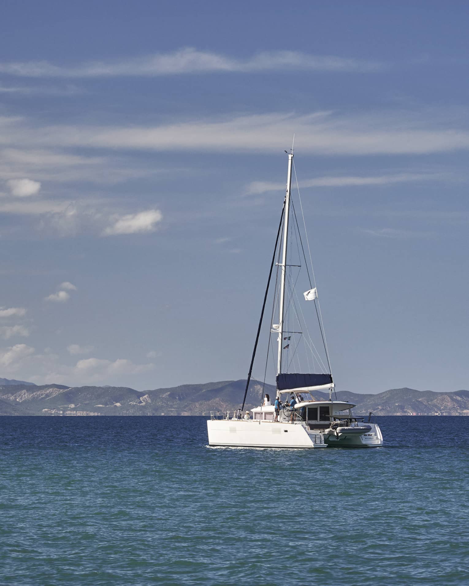 A boat sailing on the ocean with mountains in the distance.