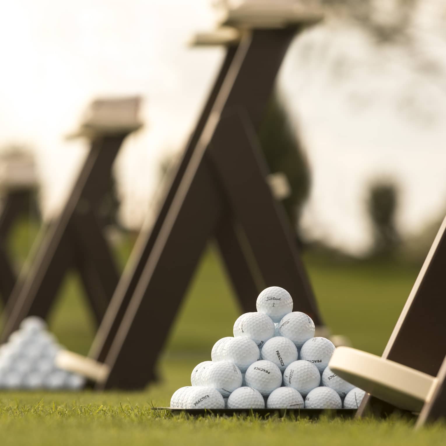 Stacks of white golf balls on lawn in front of wood panels