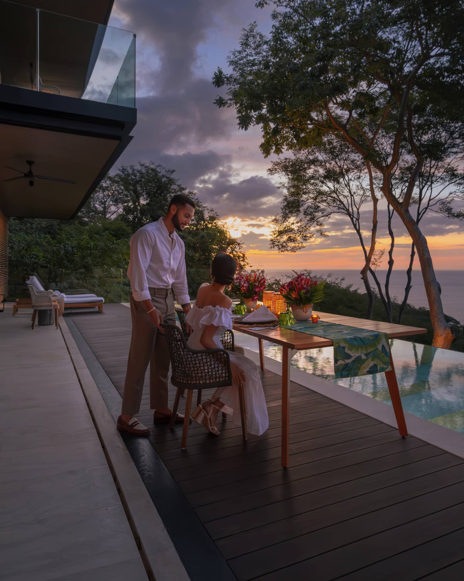 Man and woman on outdoor terrace next to infinity pool