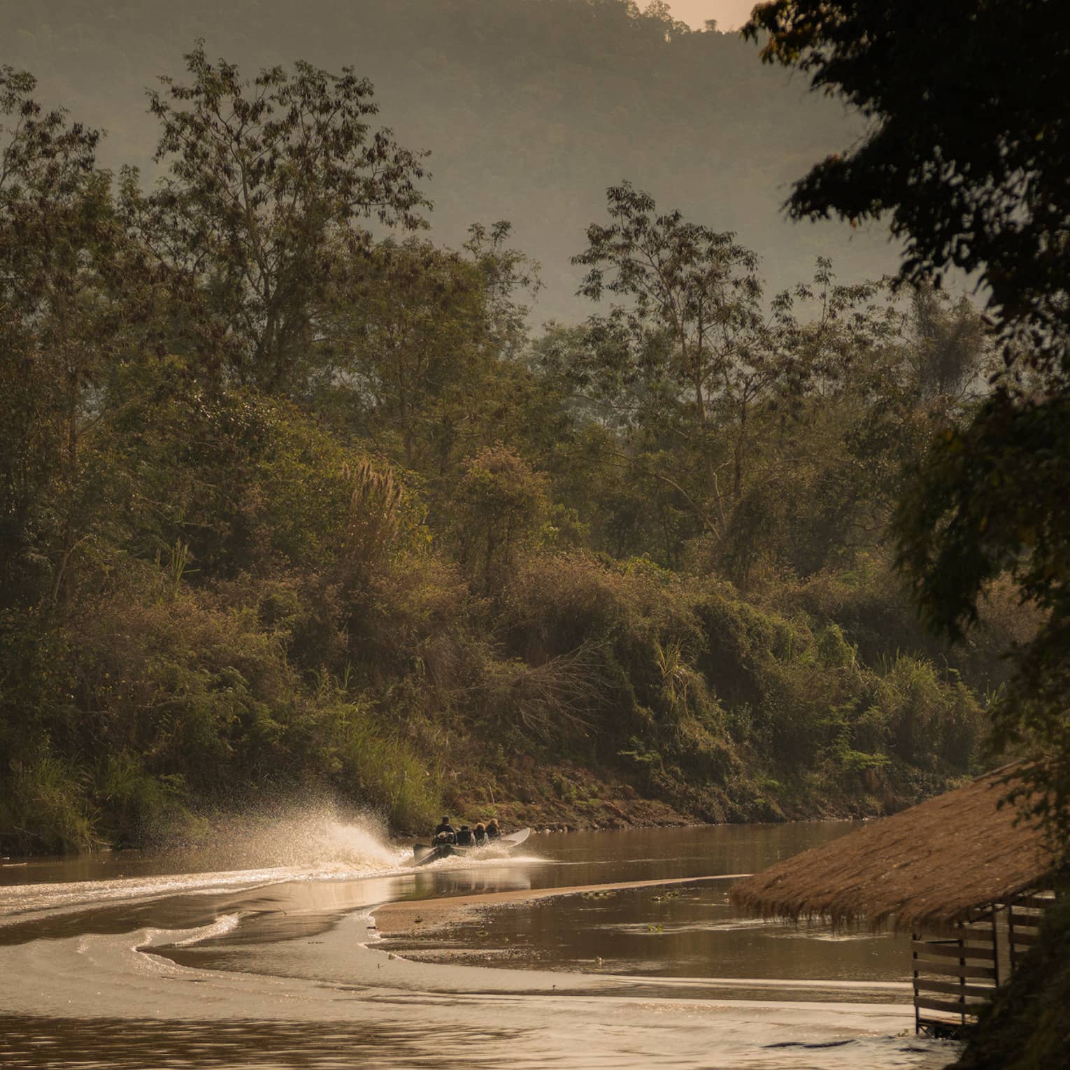 Longtail boat sprays water as it zips down the Ruak river