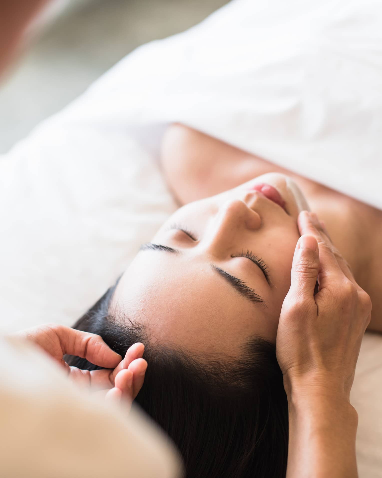 A guest receiving a soothing facial at a spa, lying on a massage table, surrounded by calming décor and soft lighting.
