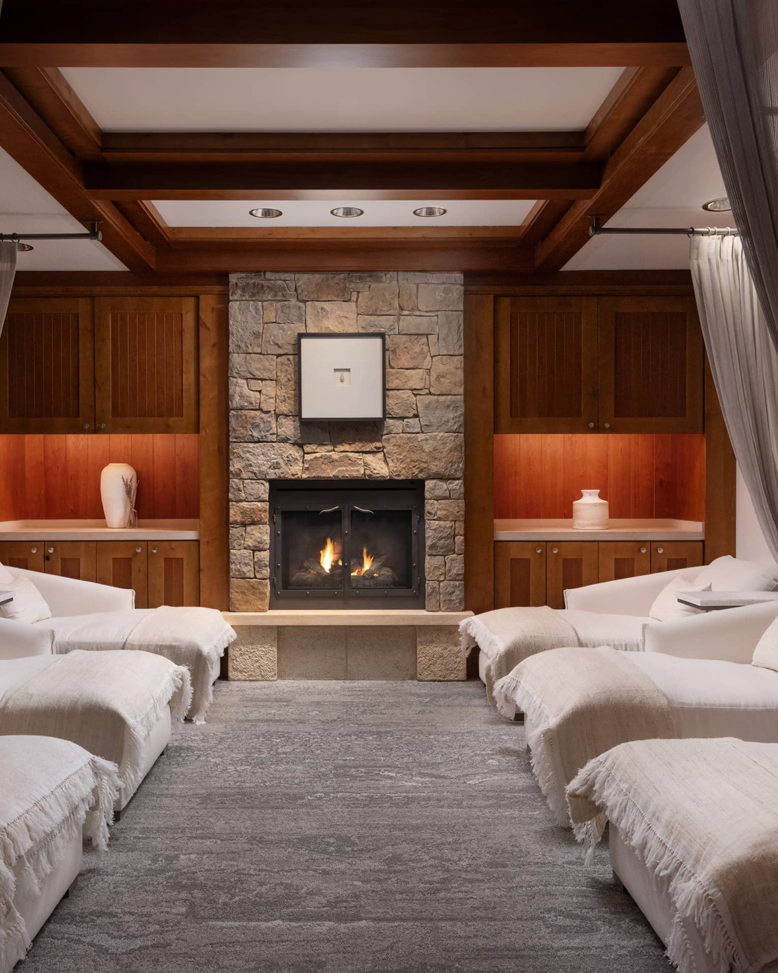 Lounge with spa beds, a fireplace and grey curtains.
