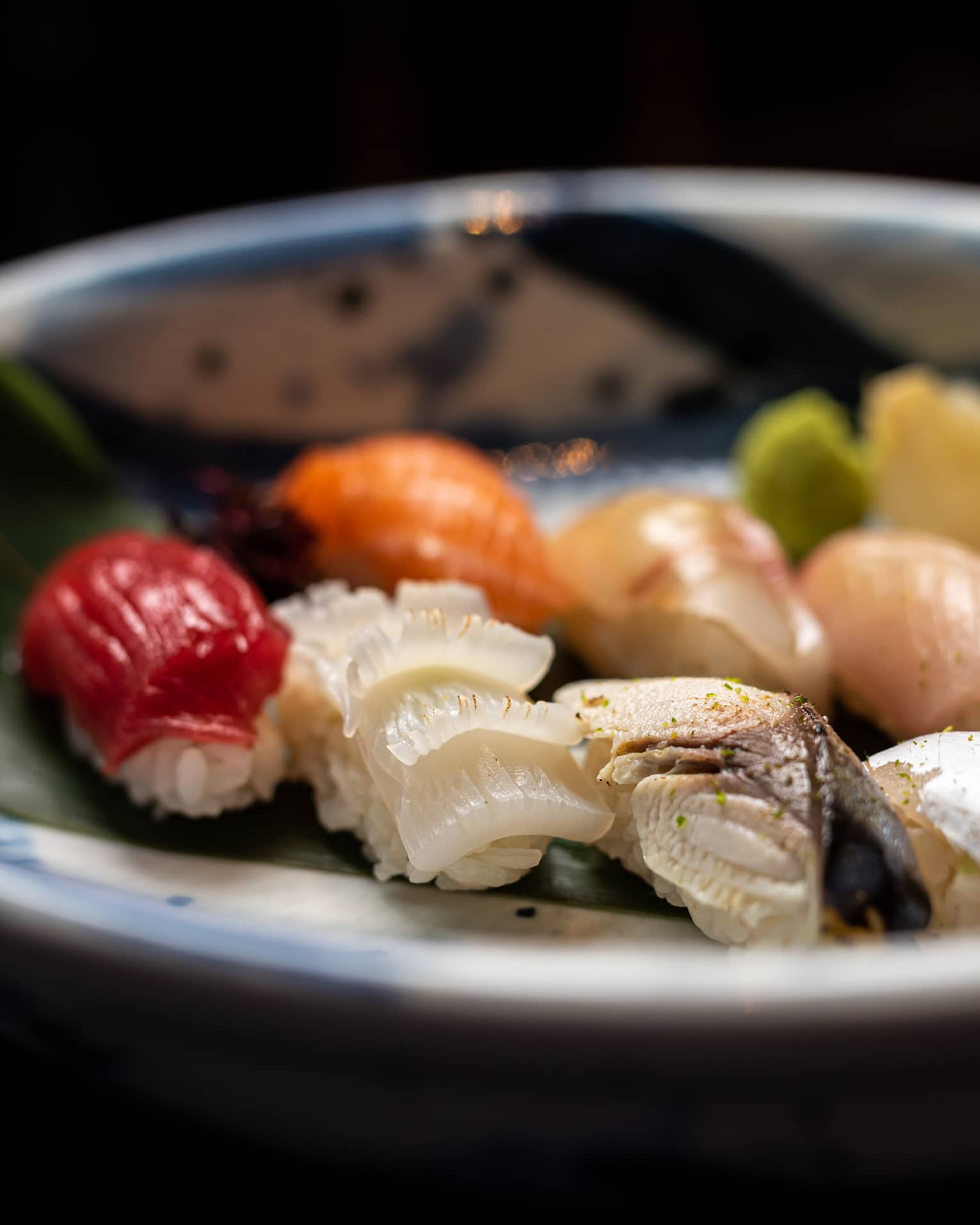 Colourful nigiri selection on palm leaf in blue-and-white bowl