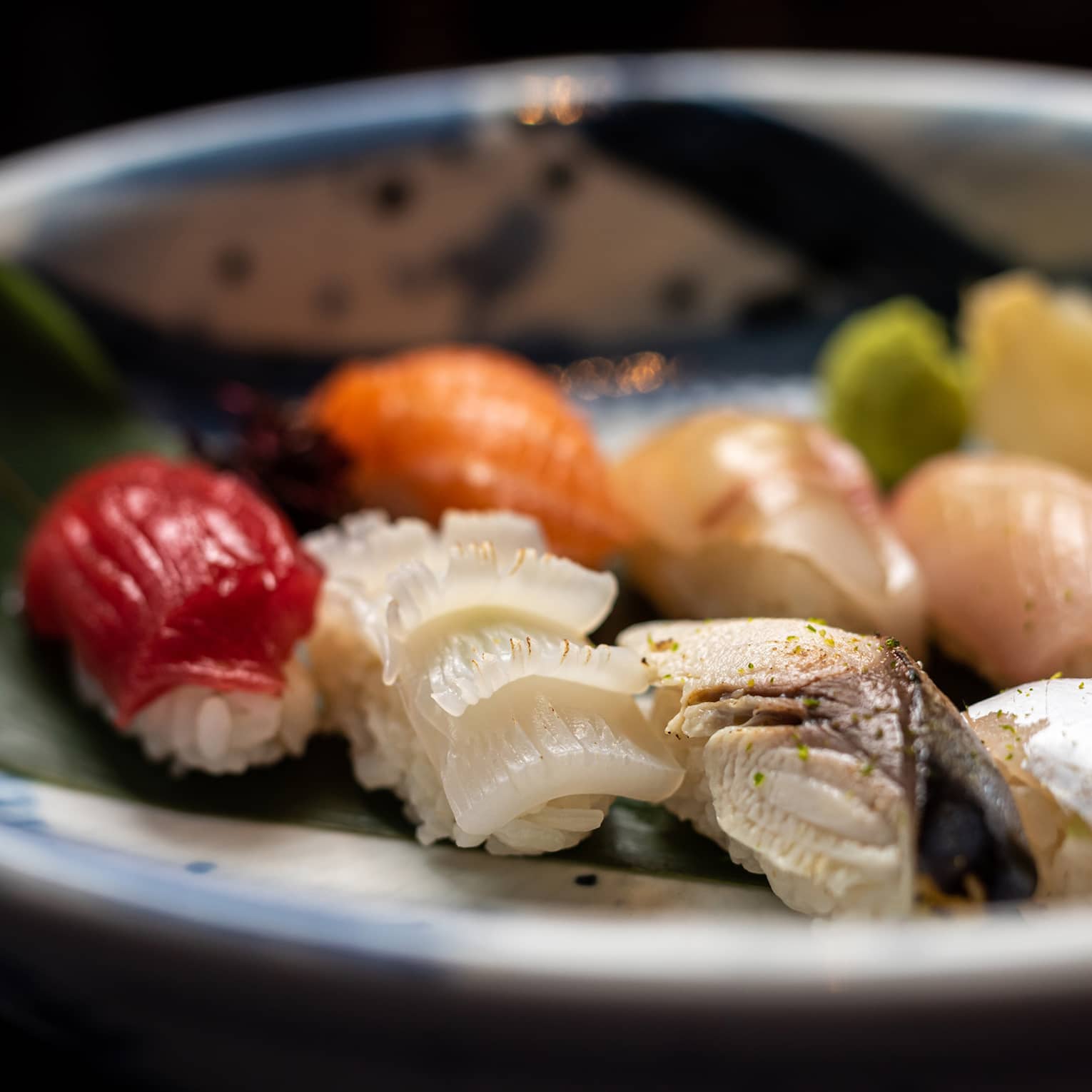 Colourful nigiri selection on palm leaf in blue-and-white bowl
