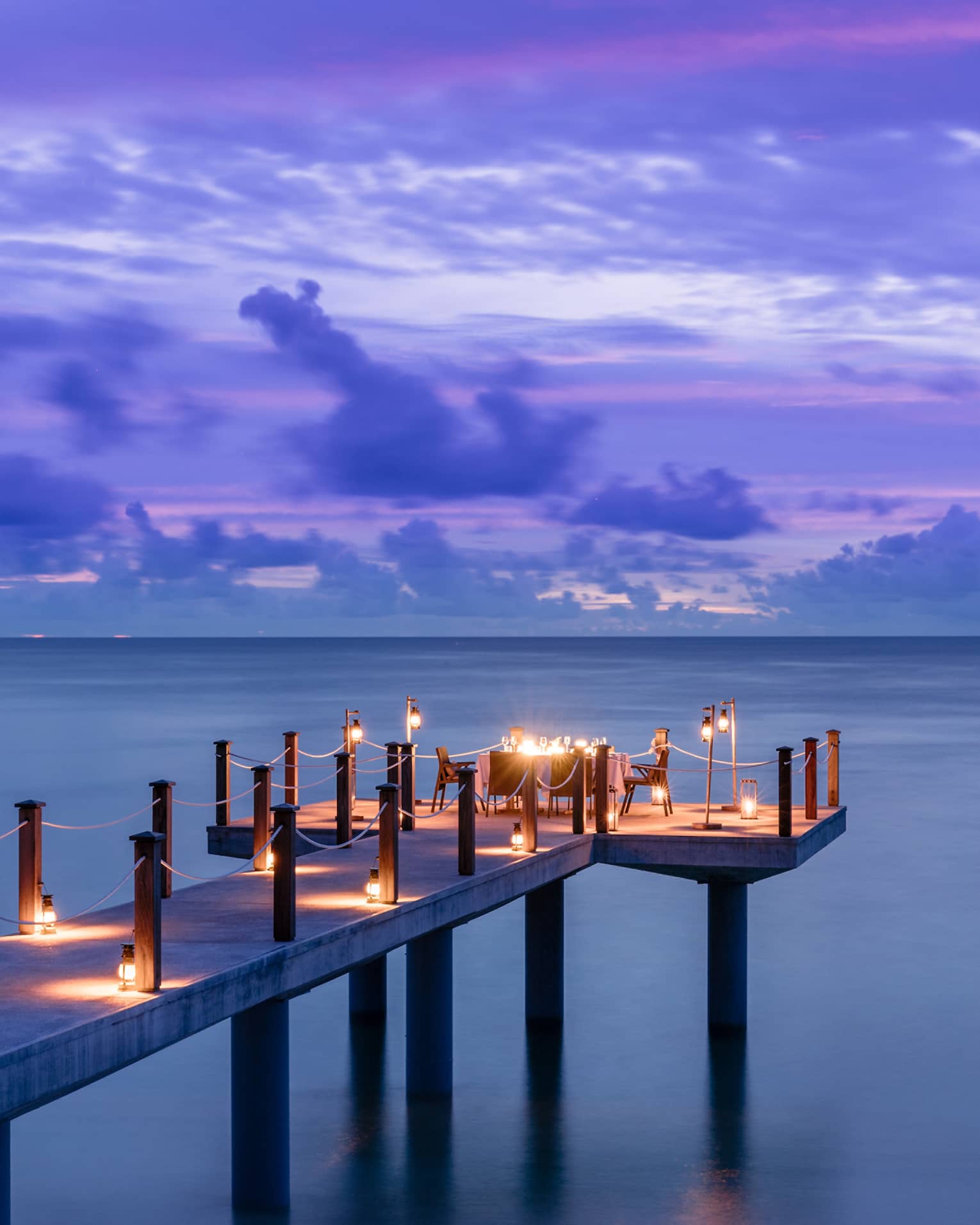 Candlelit jetty off Desroches Island with purple sunset hues