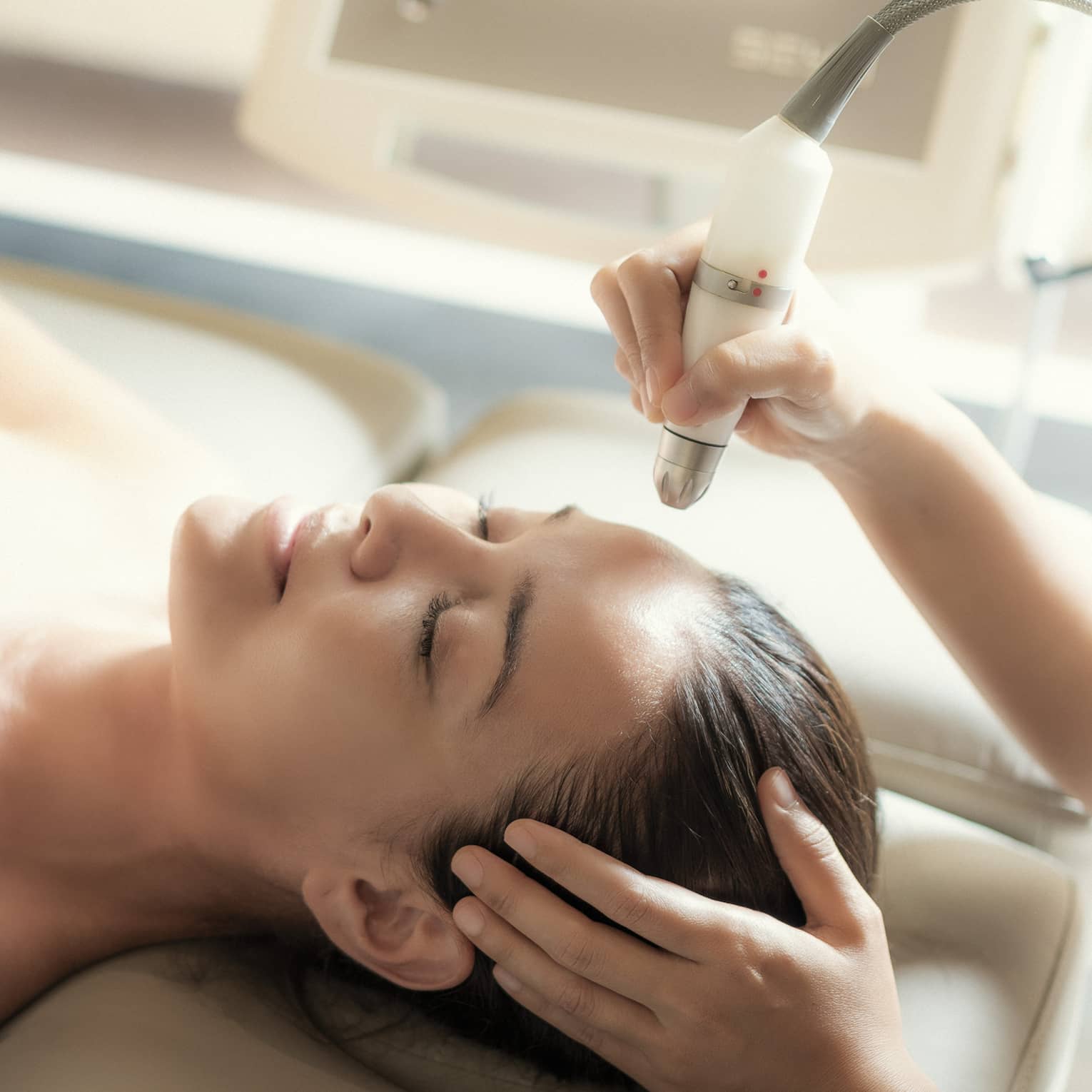 An aesthetician uses a tool on the face of a relaxing woman.