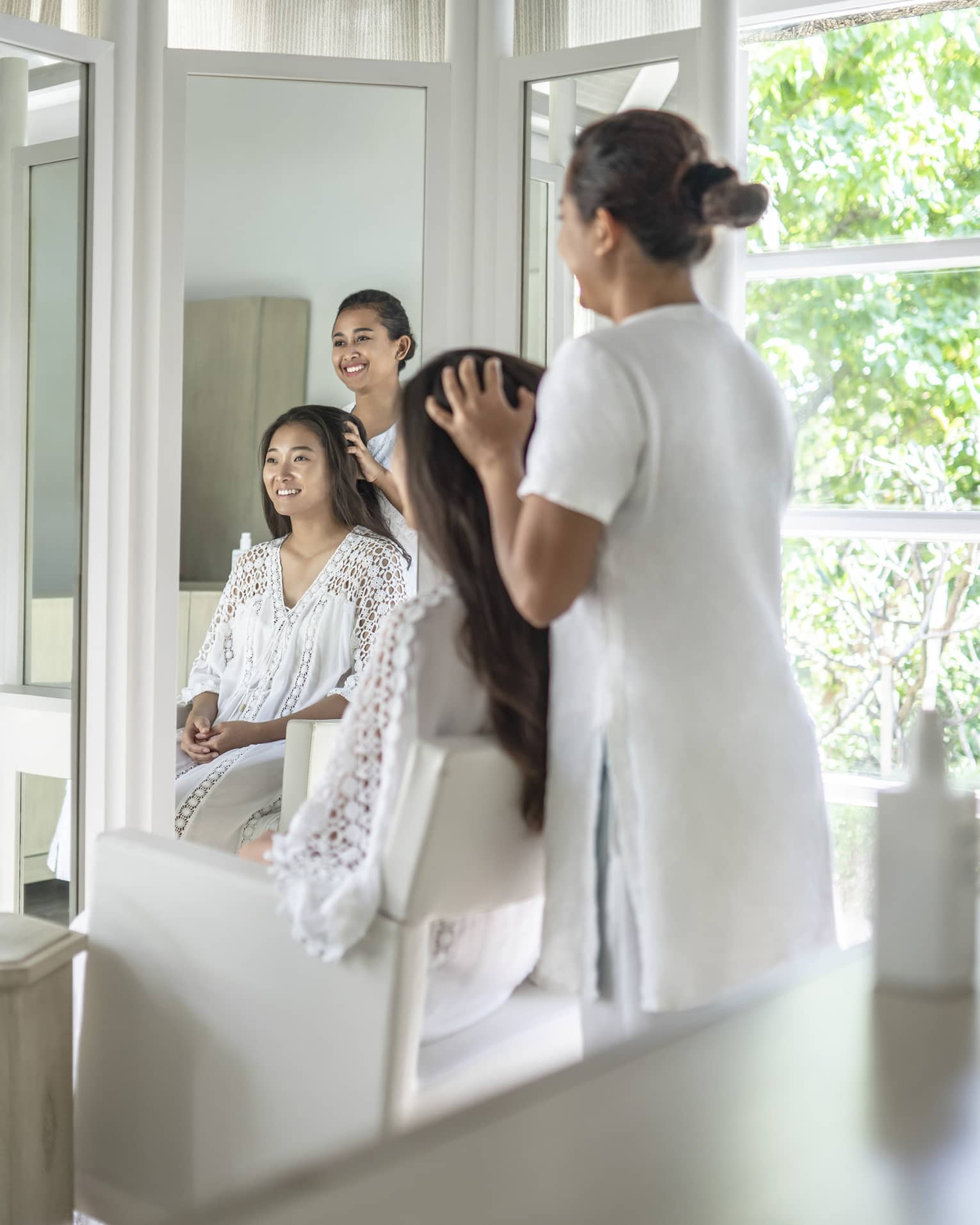 Person enjoying a hair treatment in a spa salon with large windows, surrounded by lush greenery