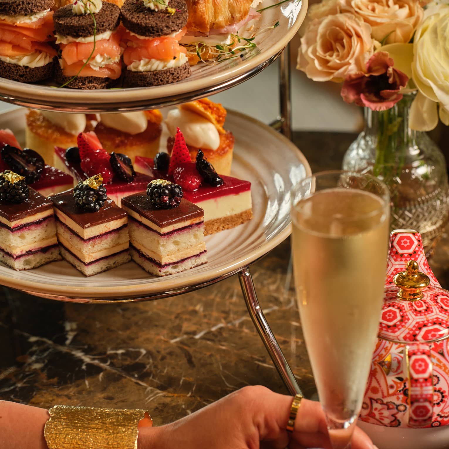 A three-tiered display of sweets beside a vase of flowers