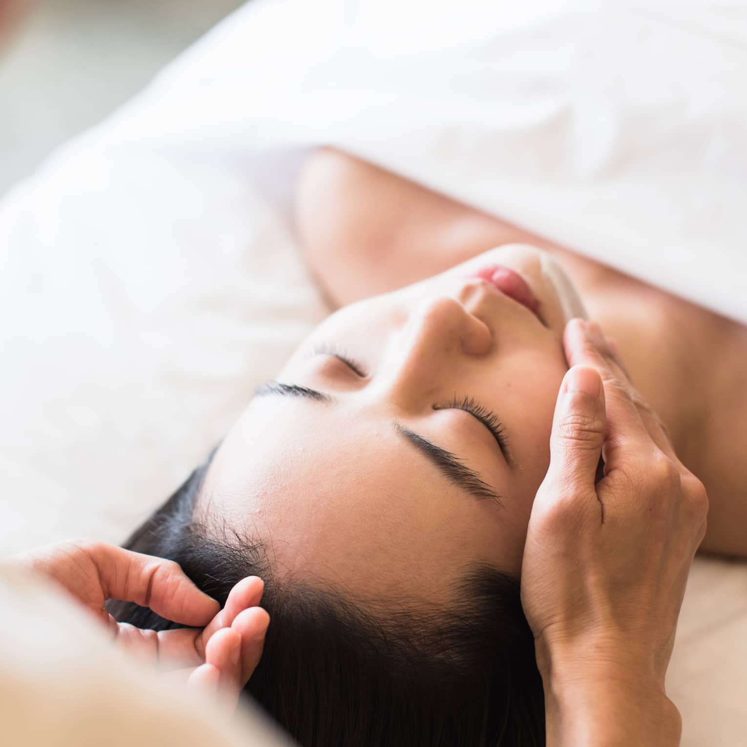A guest receiving a soothing facial at a spa, lying on a massage table, surrounded by calming décor and soft lighting.