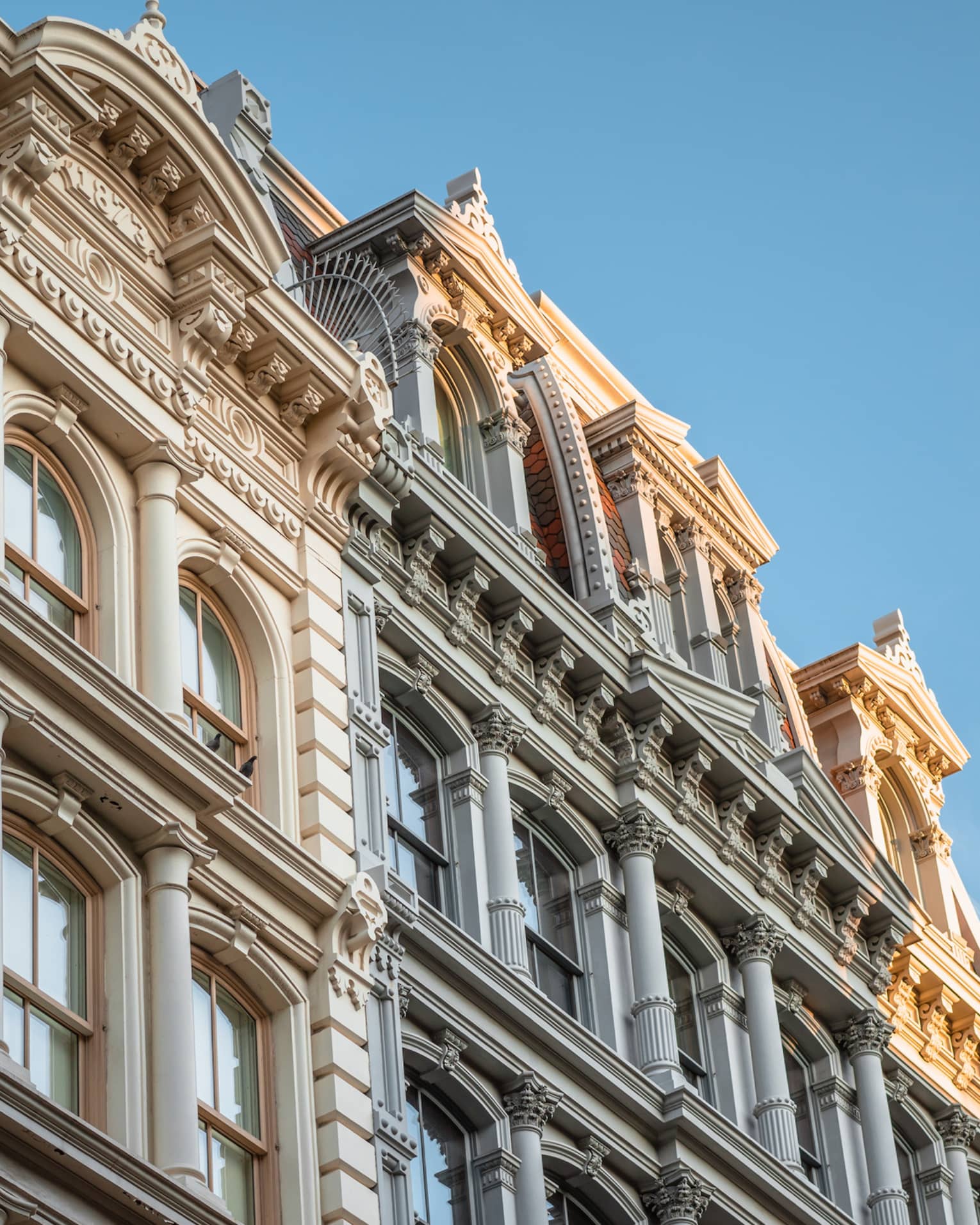 Close-up of ornate historic building facade with arched windows and decorative columns under a clear blue sky