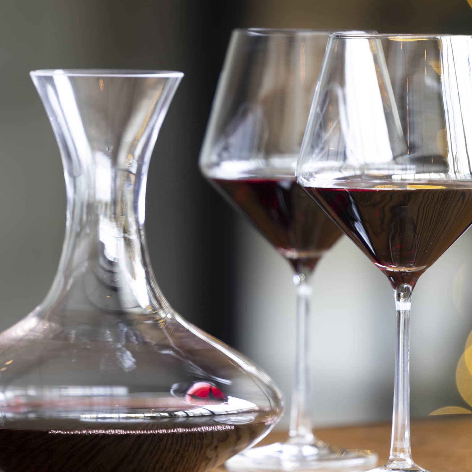 Two wine glasses on a table beside a wine pitcher
