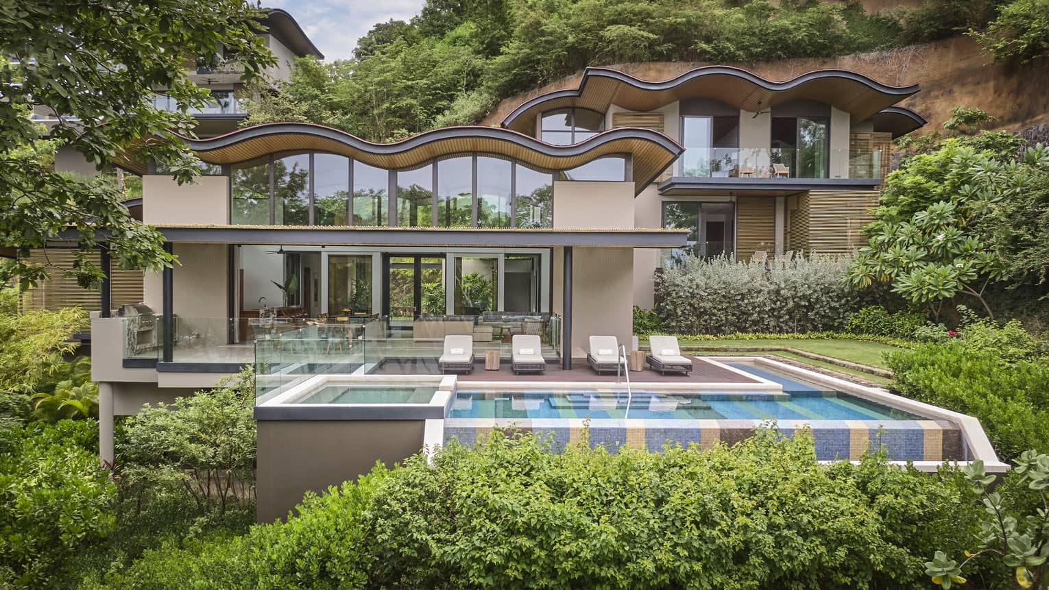 Exterior of the backside of a private villa with l-shaped pool