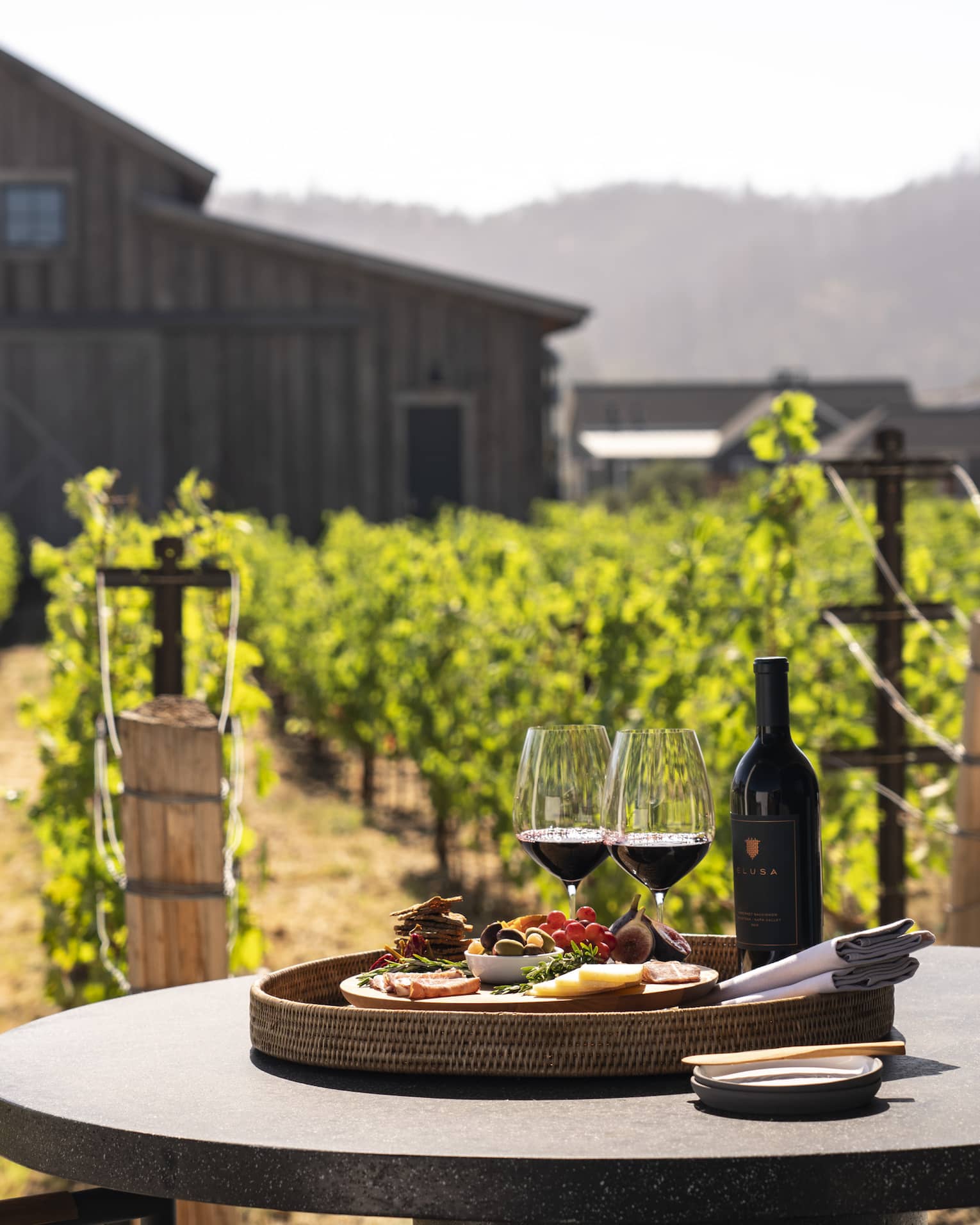 Two wine glasses with a plate of snacks on an outdoor dining table.