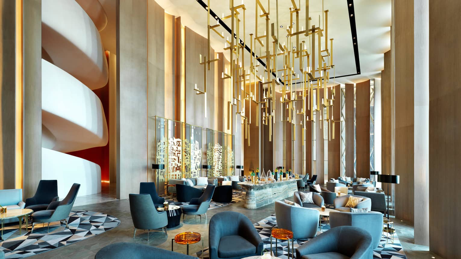 Modern dining chairs, tables in lounge with soaring ceilings, gold sculptures hanging from ceiling, wall