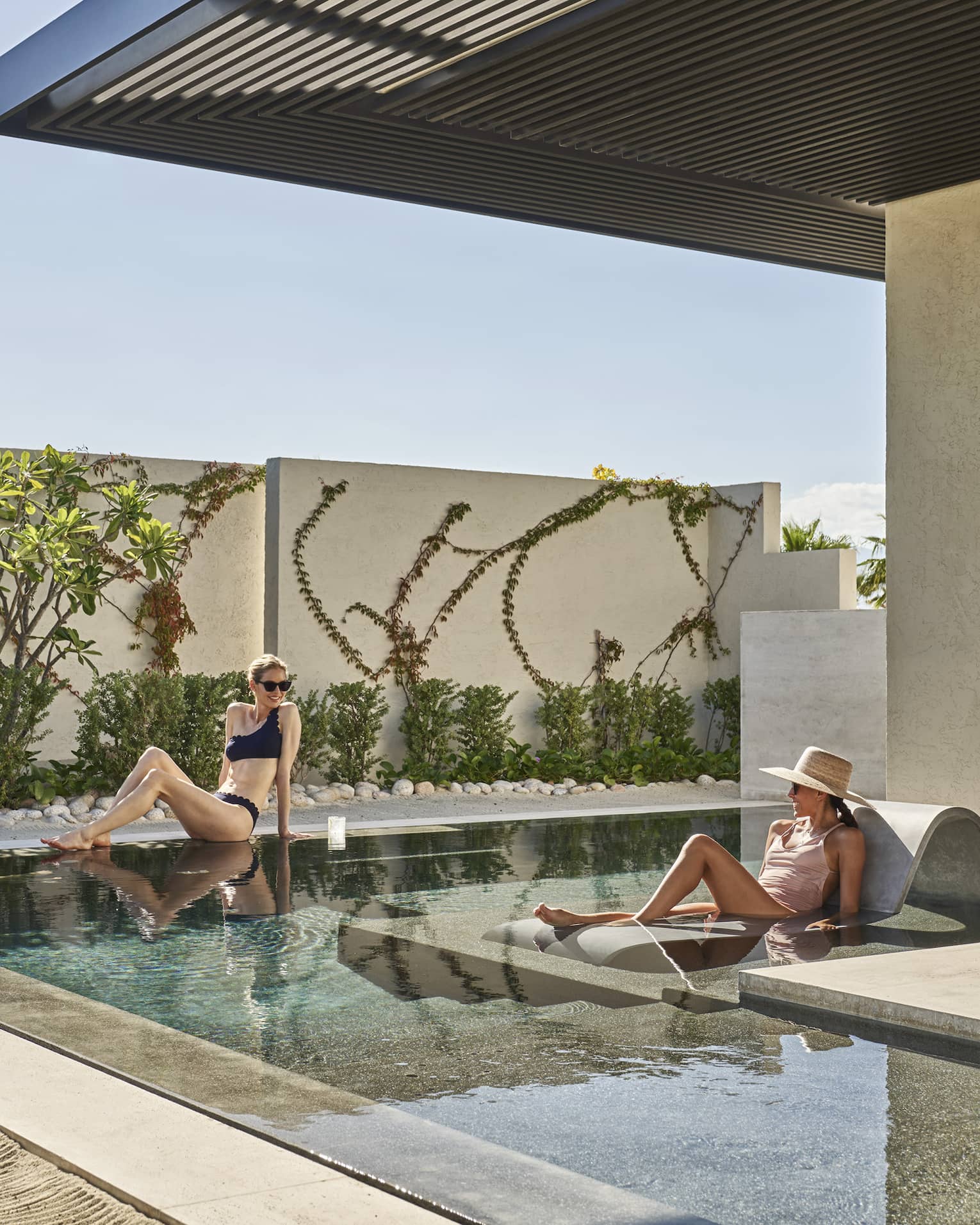 Three women lounging around a small outdoor pool.