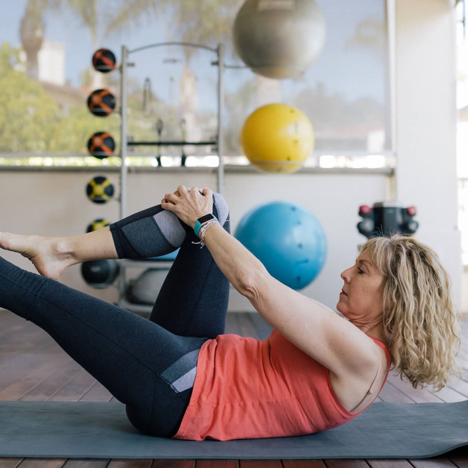Woman stretches leg on yoga mat in fitness room