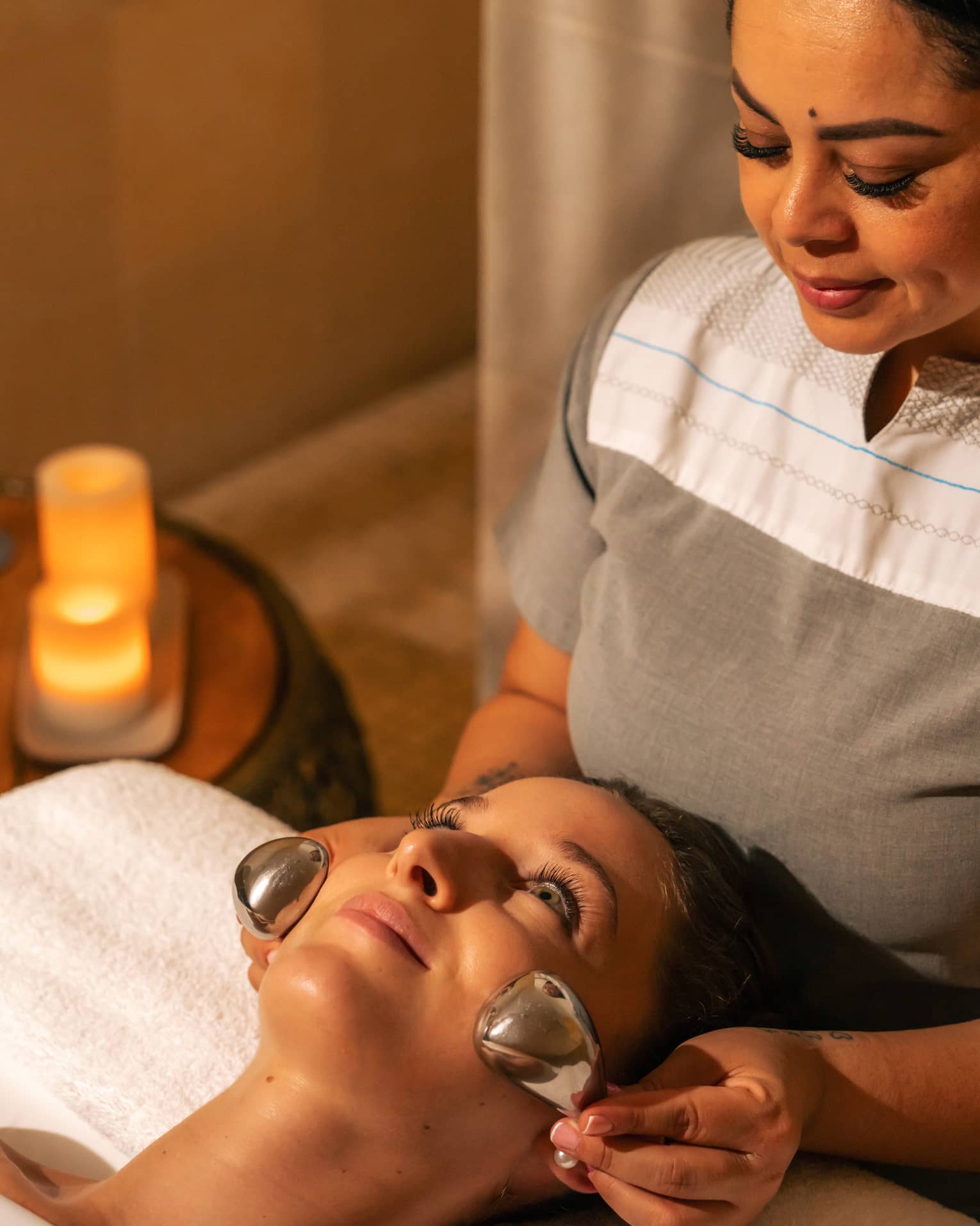 Facialist places two silver nodes on a clients face