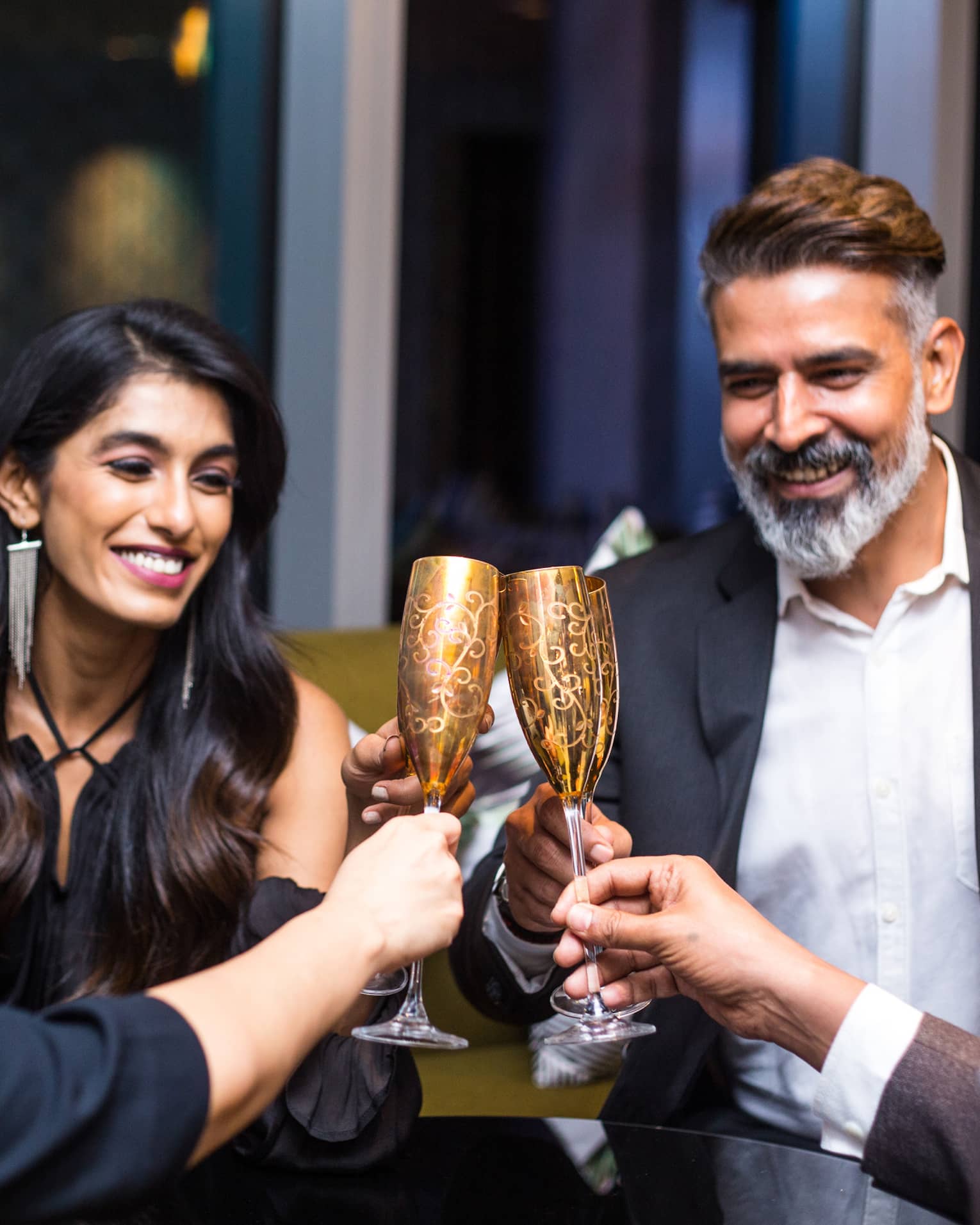 Group of smiling friends toast with gold champagne flutes
