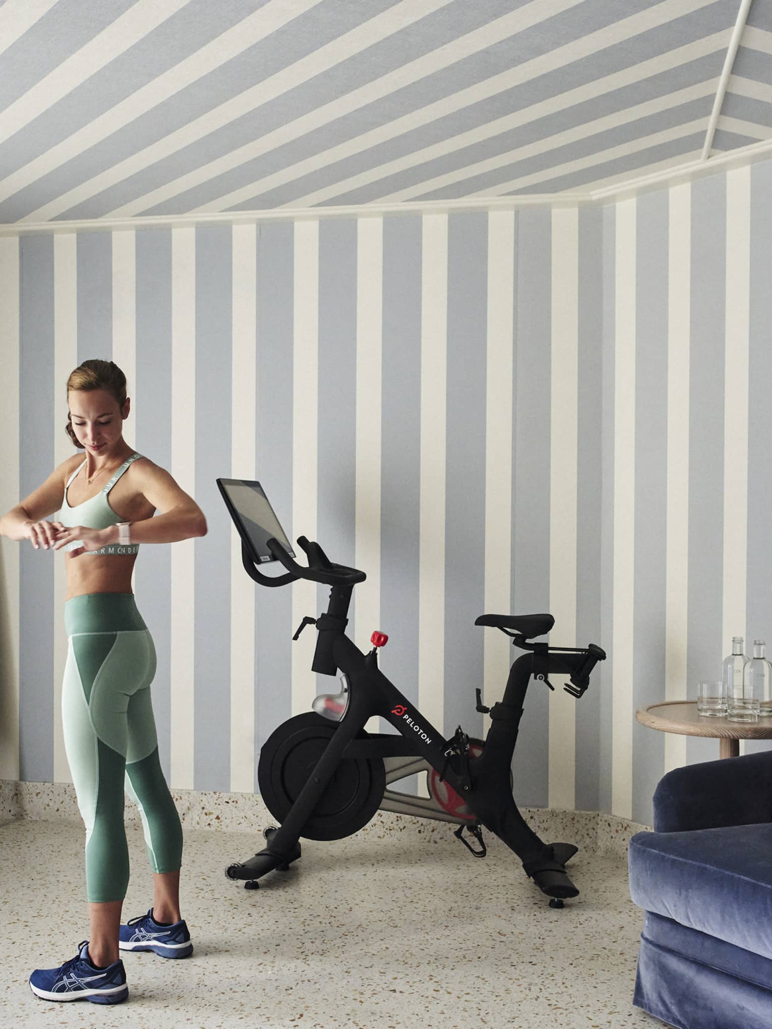 A woman in workout clothes in a hotel room with a stationary bike.