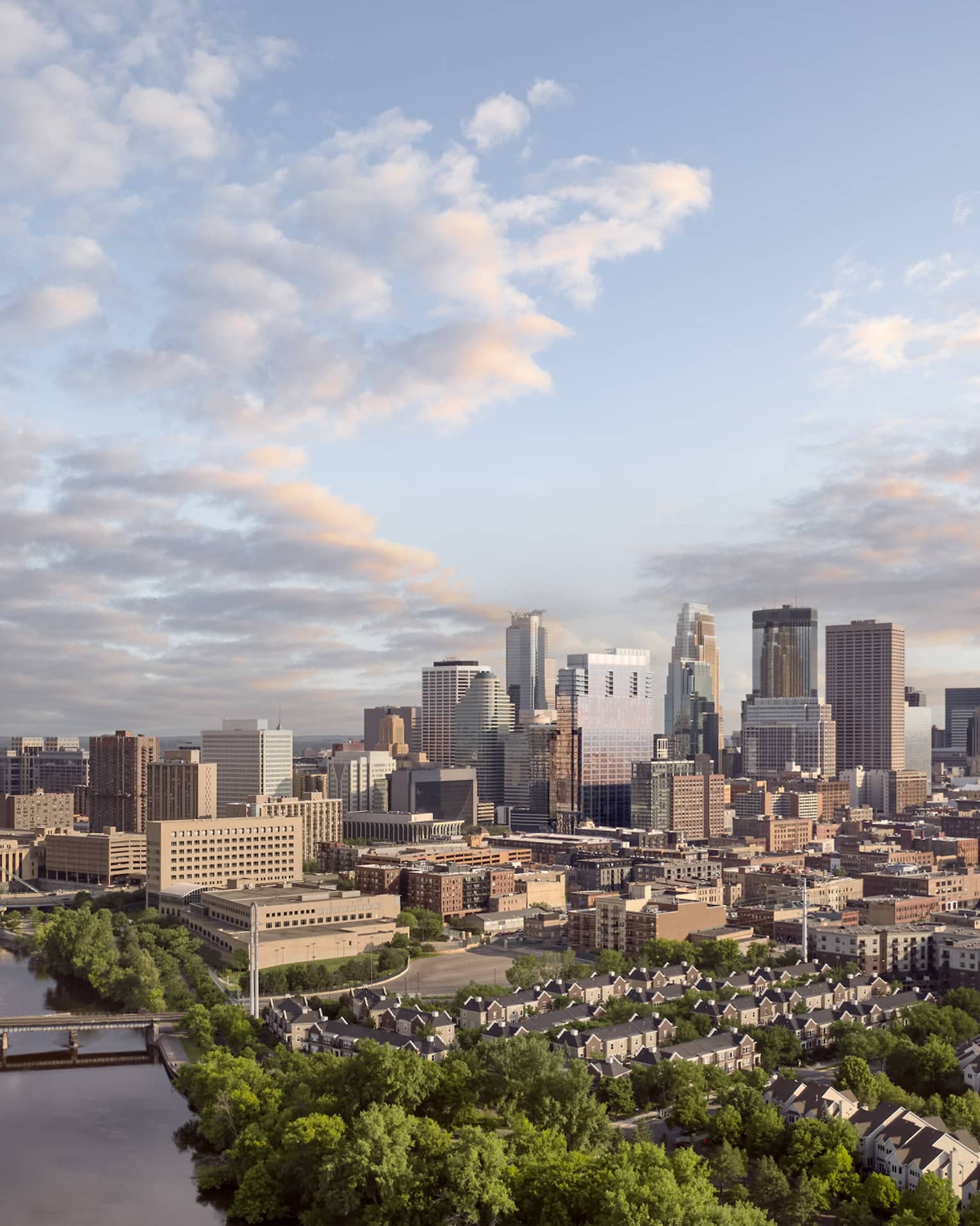 Minneapolis skyline and bridges across Mississippi River, scattered clouds and dense trees