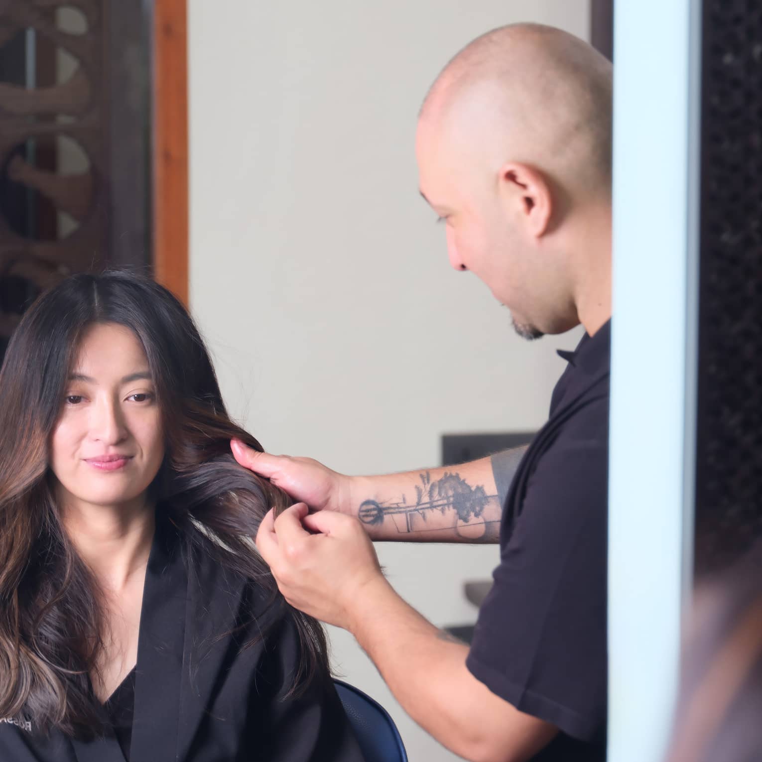 A person sitting in a salon chair while a hair stylist does their hair