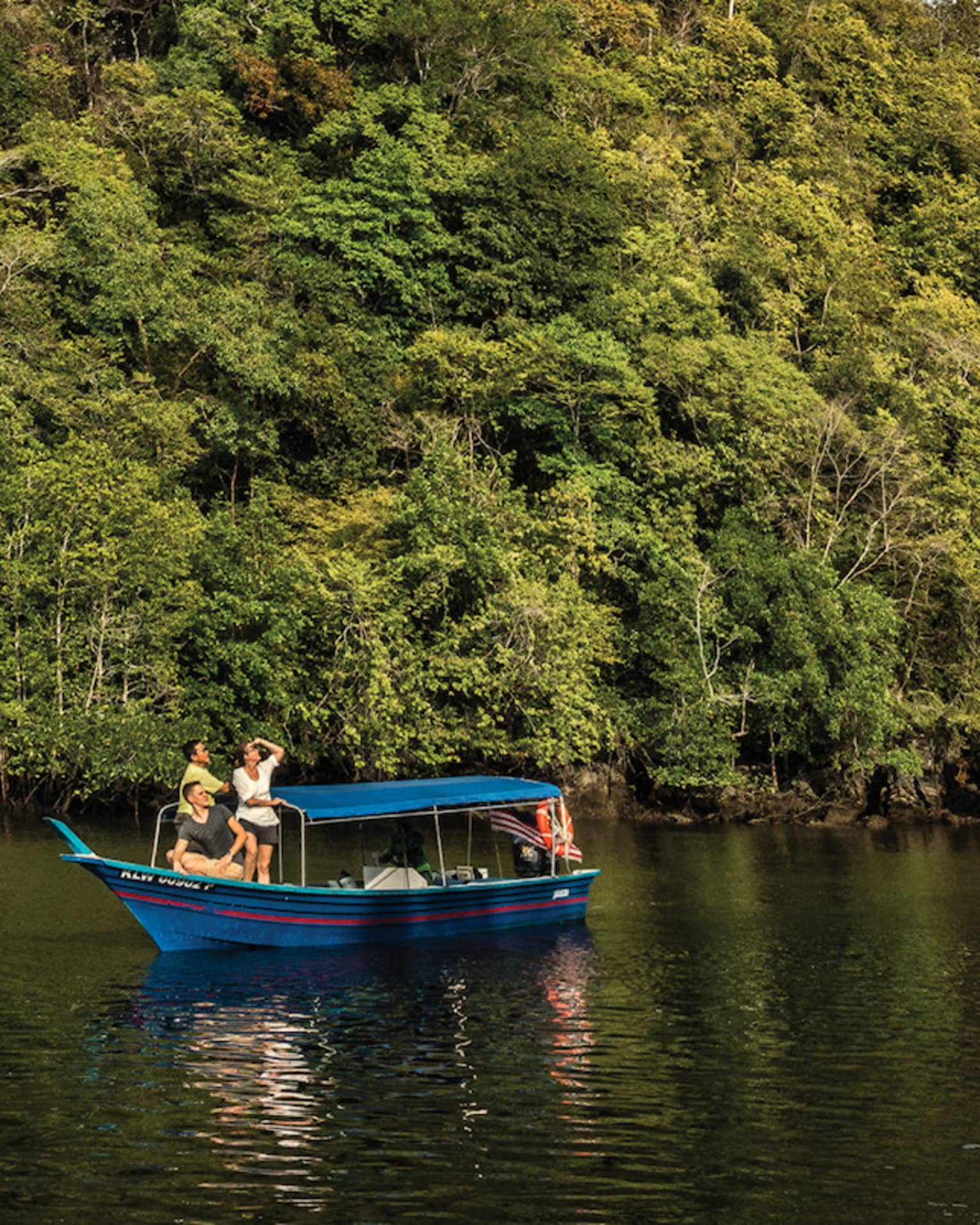 People on small blue boat on river under small rocky mountain