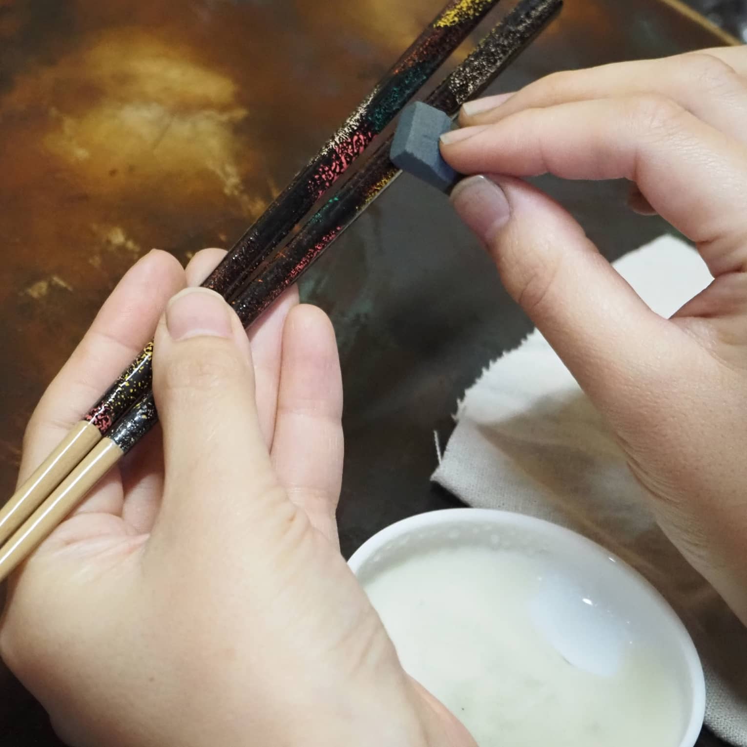 Hands apply Japanese lacquer to customize artisan chop sticks