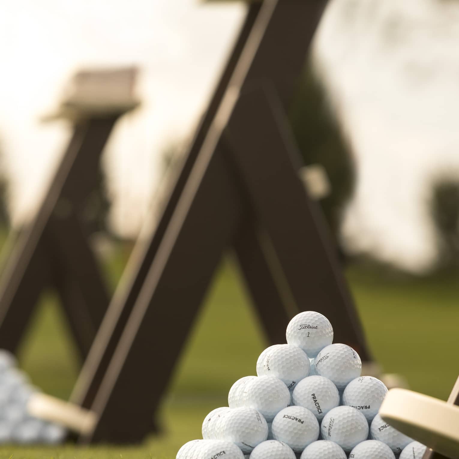 Stacks of white golf balls on lawn in front of wood panels