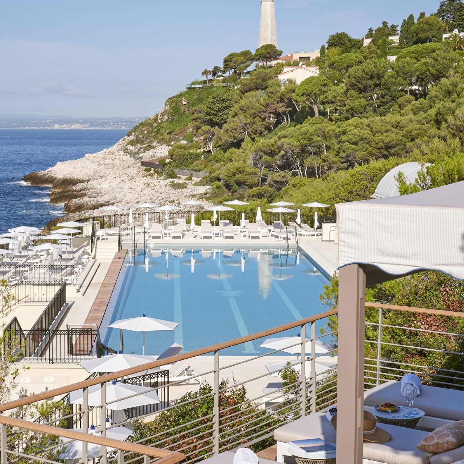 View from terrace of Club Dauphin pool, Mediterranean, green hillside and lighthouse