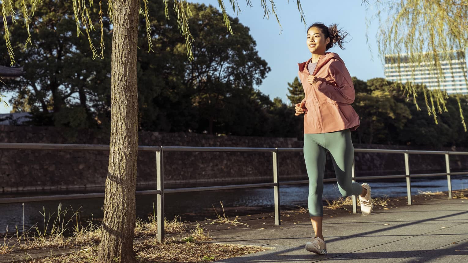 Woman jogs by Japanese temple and moat