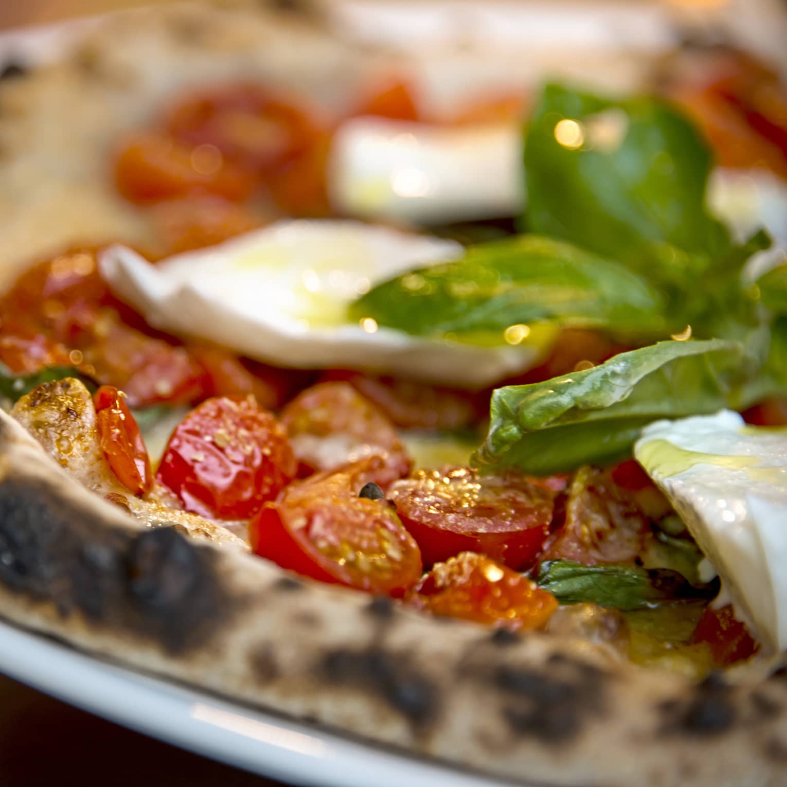 Close-up of Al Fresco signature pizza thin wheat crust, fresh cherry tomatoes, basil