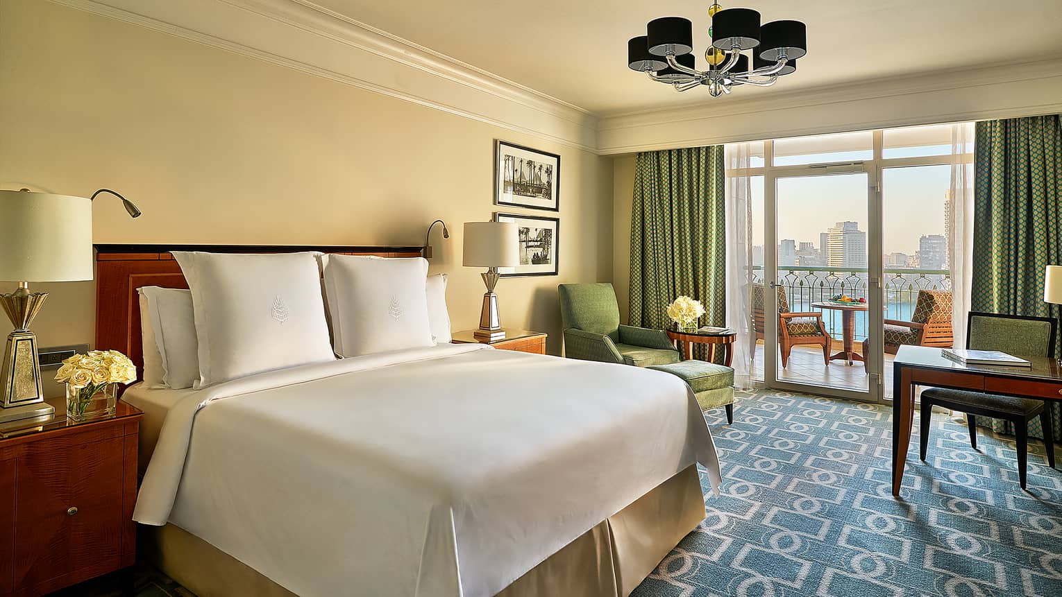 Nile View Room with white bed, blue-and-white carpet, green armchair and curtains leading to balcony