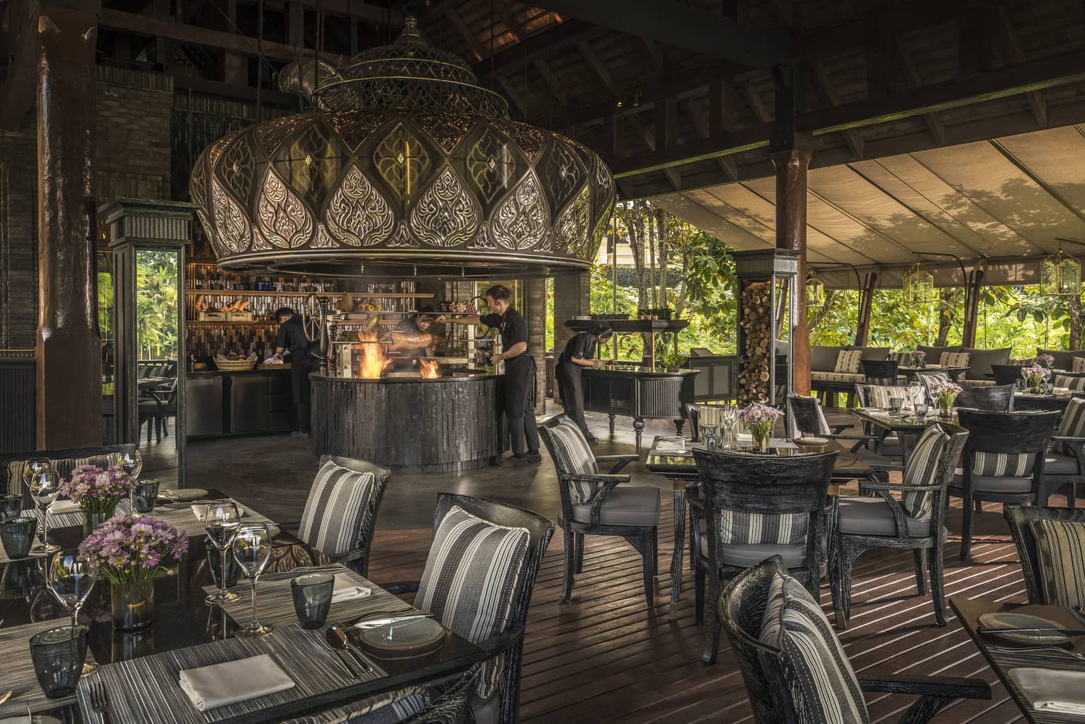 Restaurant with fire in open kitchen, dark wood floors and dining table/chairs