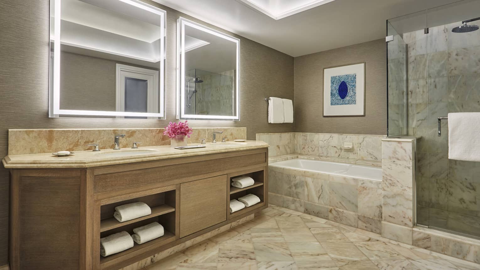 Marble bathroom with double vanity, soaking tub, glass shower and backlit mirrors
