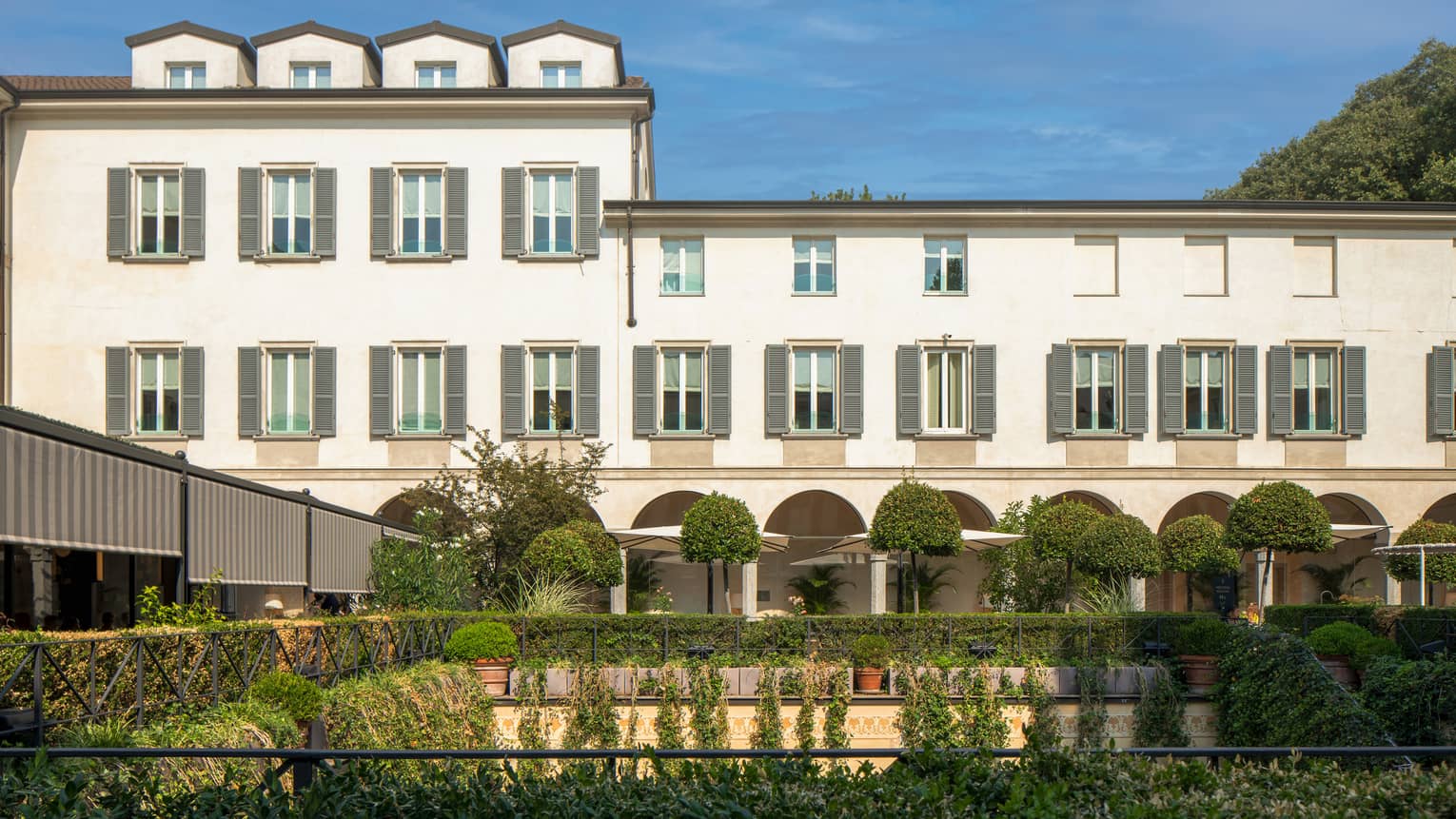 Shrubs, potted plants around rectangular courtyard garden under Four Seasons Hotel Milan building