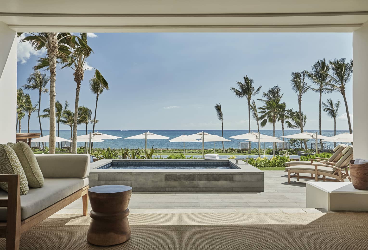 Pacific Suite open to wall to patio with stone plunge pool, lounge chairs, ocean views