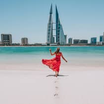 Woman on beach with bahrain city view