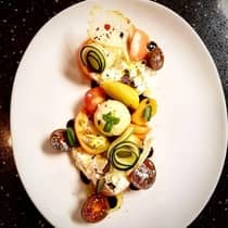 Aerial view of tomatoes, cheese, spiral zucchini, fresh basil on plate