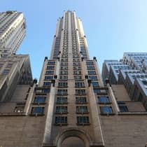 Looking up at Four Seasons Hotel New York Art Deco-style building against blue sky