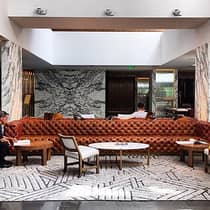 Lounge with long brown leather sofa, cocktail tables and chairs, rug