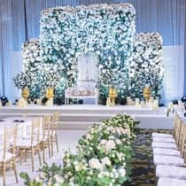 An indoor wedding reception adorned with white floral arrangements, candles and gold accents