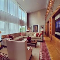 Contemporary living area with a plush beige sofa, stylish armchairs and decorative pillows. The room features floor-to-ceiling windows, allowing natural light.