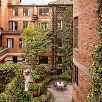 Looking down at courtyard patio surrounded by brick building, windows, green trees, shrubs