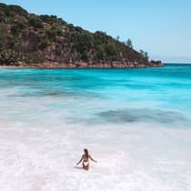 Woman wades in blue lagoon surrounded by tropical hills