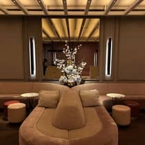 Velvet lounge seating at Marcus Restaurant and Terrace, with circular tables and stools, in front of a mirrored wall adorned with a large, white floral arrangement